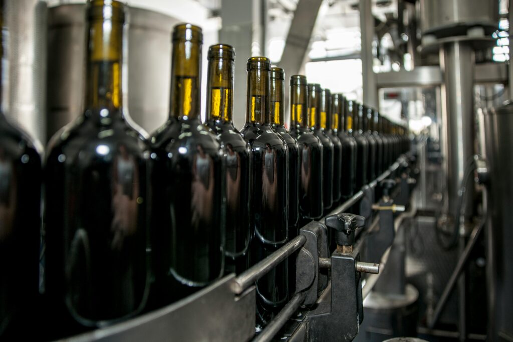 Rows of wine bottles on a production line in an industrial setting.