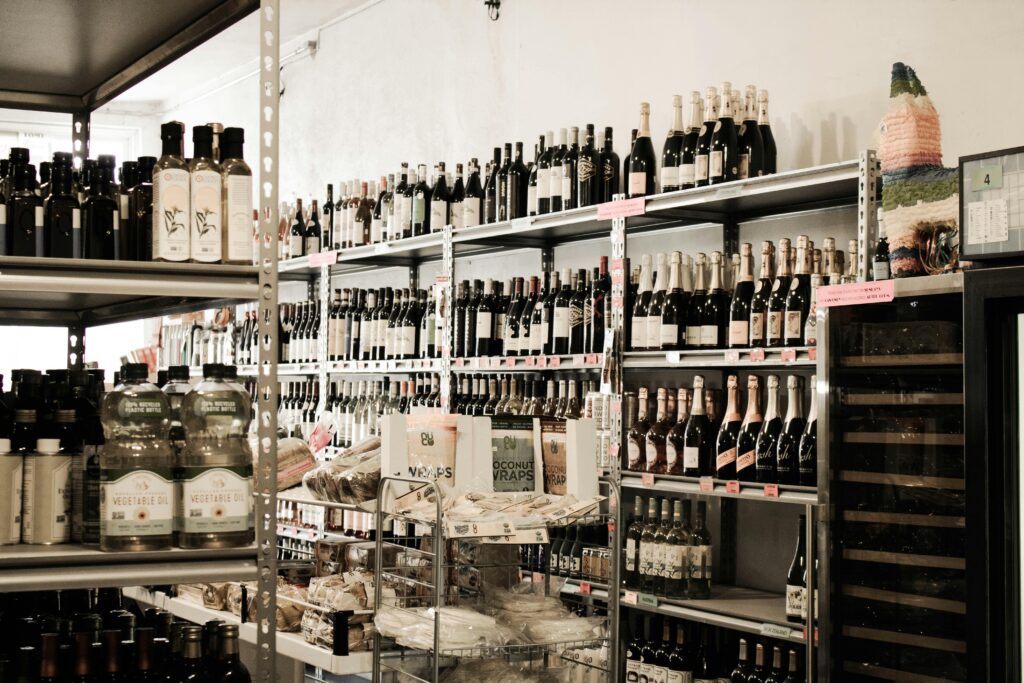 A neatly organized liquor aisle with various wine and oil bottles on shelves.